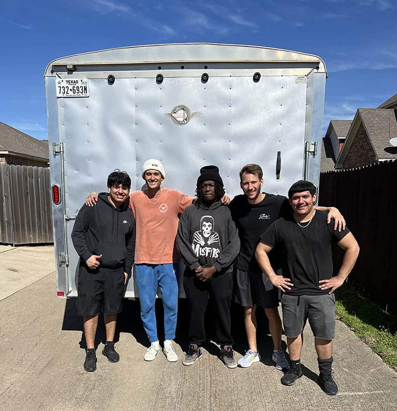 Team of 5 man is standing in front of a moving truck smiling